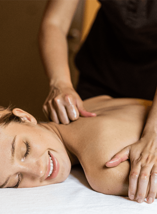 A close-up of a woman lying on a massage table while receiving a neck massage