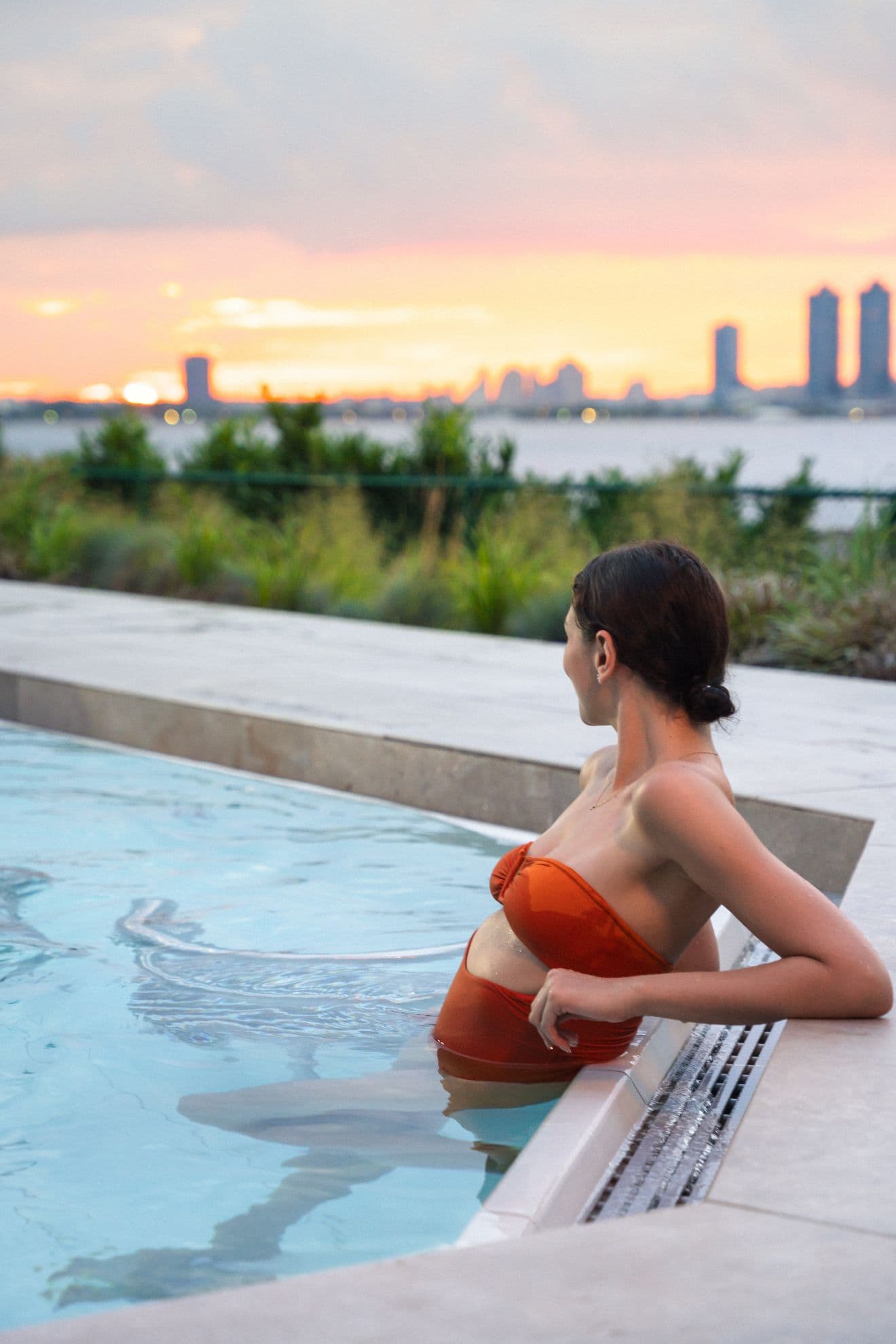 a woman in an outdoor hot tub watching the sunset